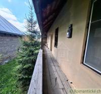 Ein Holzweg neben einem Einfamilienhaus in Pohorelá, umgeben von Grün und einem Nachbargebäude.