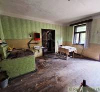 Küche in einem Einfamilienhaus mit einfacher Einrichtung, Holzboden und grünen Wänden.