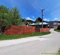 Ein Einfamilienhaus in Pohorelá mit Garten, einem Blechzaun und Strommasten an der Straße.