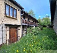 Ein Einfamilienhaus in Pohorelá mit einer Holzveranda, umgeben von Grün und wilden Blumen.