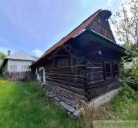 Ein Einfamilienhaus in Pohorelá mit einem alten Holzhaus und einem grasbewachsenen Garten.
