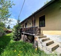 Ein Einfamilienhaus in Pohorelá mit einer Holzterrasse, Treppen und einem Rasen mit Blumen.