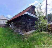 Ein Holzfamilienhaus in Pohorelá, umgeben von Grün, mit einem Blechdach.