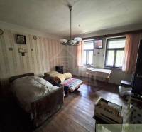 Ein Zimmer in einem Einfamilienhaus mit einem Bett, Holzboden und gemusterten Tapeten.