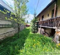 Ein Einfamilienhaus in Pohorelá, ein grasbewachsener Hof mit Blumen und Bäumen, eine Holzveranda.
