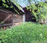 Holzbauten und ein überwucherter Garten bei einem Einfamilienhaus in Pohorelá.