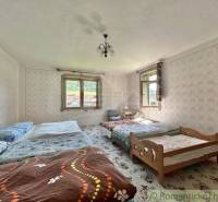 Schlafzimmer in einem Einfamilienhaus mit mehreren Betten, Tapeten und Fenstern mit Aussicht.