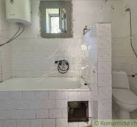 Badezimmer in einem Einfamilienhaus mit Badewanne, Toilette und Gas-Wassererhitzer.