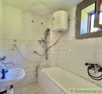 Ein einfaches Badezimmer in einem Einfamilienhaus mit einer Badewanne und einem Boiler an der Wand.