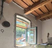 Holzdecke und offenes Fenster mit Aussicht im Innenraum eines Einfamilienhauses.