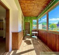 Veranda mit Glas in einem Einfamilienhaus mit Holzstühlen und Blick auf den Garten.