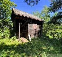 Eine Holzhütte umgeben von Grün in den Gärten von Malacky, der ideale Ort zum Entspannen.