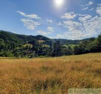 Die Landschaft in der Umgebung von Žarnovica, gesäumt von Wiesen und Wäldern, unter blauem Himmel.