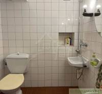 Badezimmer mit Toilette, Waschbecken, Lichtern und weißen Fliesen, besondere Immobilie.