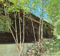 Eine Holzhütte in Liptovský Mikuláš, umgeben von Bäumen und Grün.