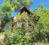 Eine Holzhütte in Liptovský Mikuláš, umgeben von üppigem Grün und Bäumen.