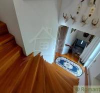 Eine Holztreppe in einem Einfamilienhaus mit Bändern und Jagdtrophäen an der Wand.