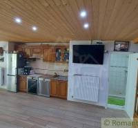 Eine Küche in einem Einfamilienhaus mit Holzdecke, Küchenzeile und einem Fernseher an der Wand.