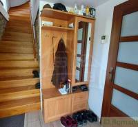 Innenraum eines Einfamilienhauses mit Holztreppe, Schrank und Steinwand.