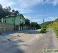 Ein Einfamilienhaus in Dobrá Voda an der Straße, umgeben von grünen Hügeln und Bäumen.
