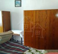 Ein Zimmer in einem Einfamilienhaus mit antiken Schränken und einem Bett mit einer bunten Decke.