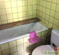 Ein Badezimmer in einem Einfamilienhaus mit einer Badewanne und einer Toilette, umgeben von gelben Fliesen.