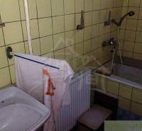 Badezimmer in einem Einfamilienhaus mit Waschbecken, Badewanne und gelben Fliesen.