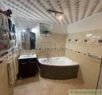 Badezimmer in einem Einfamilienhaus mit Badewanne, Waschbecken, Fliesen und dekorativen Details.