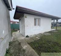 Ein Gartenpavillon bei einem Einfamilienhaus auf einer befestigten Fläche mit Rasen und Zaun.