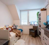 Kinderzimmer in einem Einfamilienhaus mit Bett, Sessel, Regalen und Fenster.