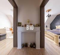 Zwei Zimmer in einem Einfamilienhaus, verbunden durch einen Flur mit dekorativem Kamin.