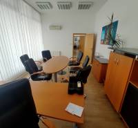 Büros ausgestattet mit Möbeln mit rundem Tisch, Sesseln und Schränken.