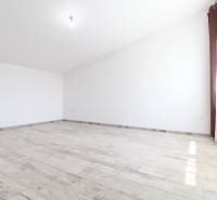 Ein geräumiges und helles Zimmer in einem Einfamilienhaus mit weißen Wänden und Parkettboden.