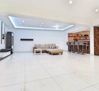 Innenraum eines Einfamilienhauses mit geräumigem Wohnzimmer, Barhockern und Sitzmöbeln.