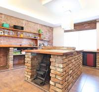 Eine Küche in einem Einfamilienhaus mit Backsteindetails und Holzregalen.