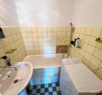 Badezimmer mit Badewanne, Waschbecken und Waschmaschine in einer 2-Zimmer-Wohnung.