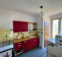 Küche einer 2-Zimmer-Wohnung mit roten Schränken und einem älteren Gasherd.