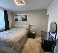 Schlafzimmer in einem Einfamilienhaus mit Bett, Lampe, Tisch und Wanddekoration.