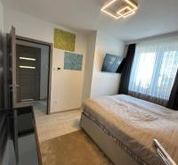 Ein Schlafzimmer in einem Einfamilienhaus mit Licht, Fernseher, Bildern und einem großen Fenster.