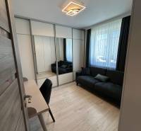 Ein Zimmer in einem Einfamilienhaus mit einem schwarzen Sofa, einem Schreibtisch und einem Spiegelschrank.