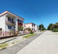 Einfamilienhäuser in der Školská-Straße in Voderady, blauer Himmel, Straße und Grünflächen.