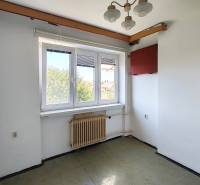 Ein Zimmer in einem Einfamilienhaus mit Fenster, Heizkörper, Kronleuchter und sichtbarer Steckdose in der Ecke.