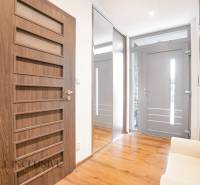 Ein Flur in einem Einfamilienhaus mit Holzboden, Spiegel und Türen mit geometrischen Elementen.