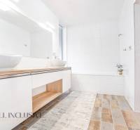 Ein Badezimmer in einem Einfamilienhaus mit Waschbecken, weißen Wänden und Holzboden.