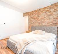 Ein Schlafzimmer in einem Einfamilienhaus mit einer Steinwand, einem eleganten Bett und dekorativen Accessoires.