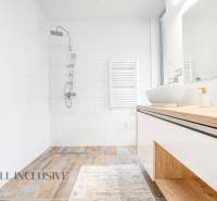 Badezimmer in einem Einfamilienhaus mit Waschbecken, Dusche und weißen Fliesen.