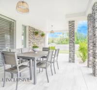 Die Terrasse des Einfamilienhauses in Dunajský Klátov mit Esstisch und Gartenpflanzen.
