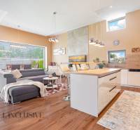 Wohnzimmer in einem Einfamilienhaus mit Küche, grauem Sofa und Esstisch.
