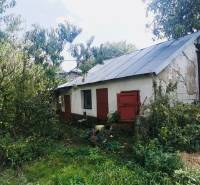 Ein Einfamilienhaus in Sobrance, umgeben von dichtem Grün, mit alter Putzfassade und roten Türen.