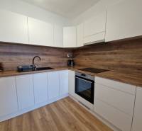 Weiße Küche in einer 2-Zimmer-Wohnung mit Holzarbeitsplatte und Holzboden.